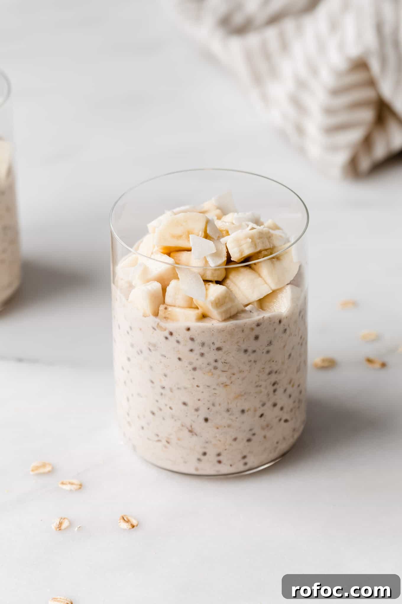 Banana Cream Pie Overnight Oats Recipe for Creamy Make-Ahead Breakfast 10 a glass of banana overnight oats topped with banana and coconut flakes.