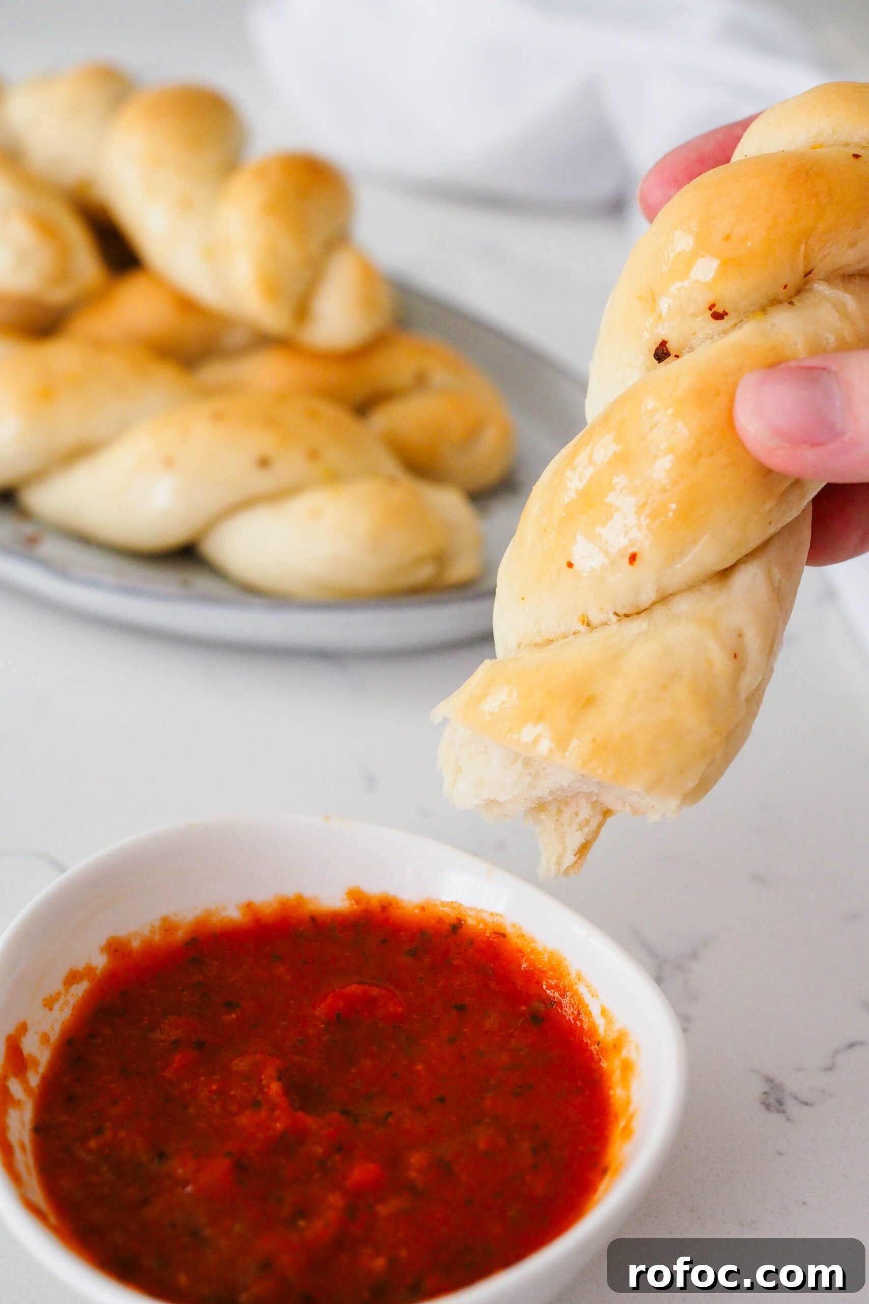 Crispy Garlic Breadsticks Recipe with Herb Butter Dip 2 Half of a twisted garlic breadstick is dipped into marinara sauce.