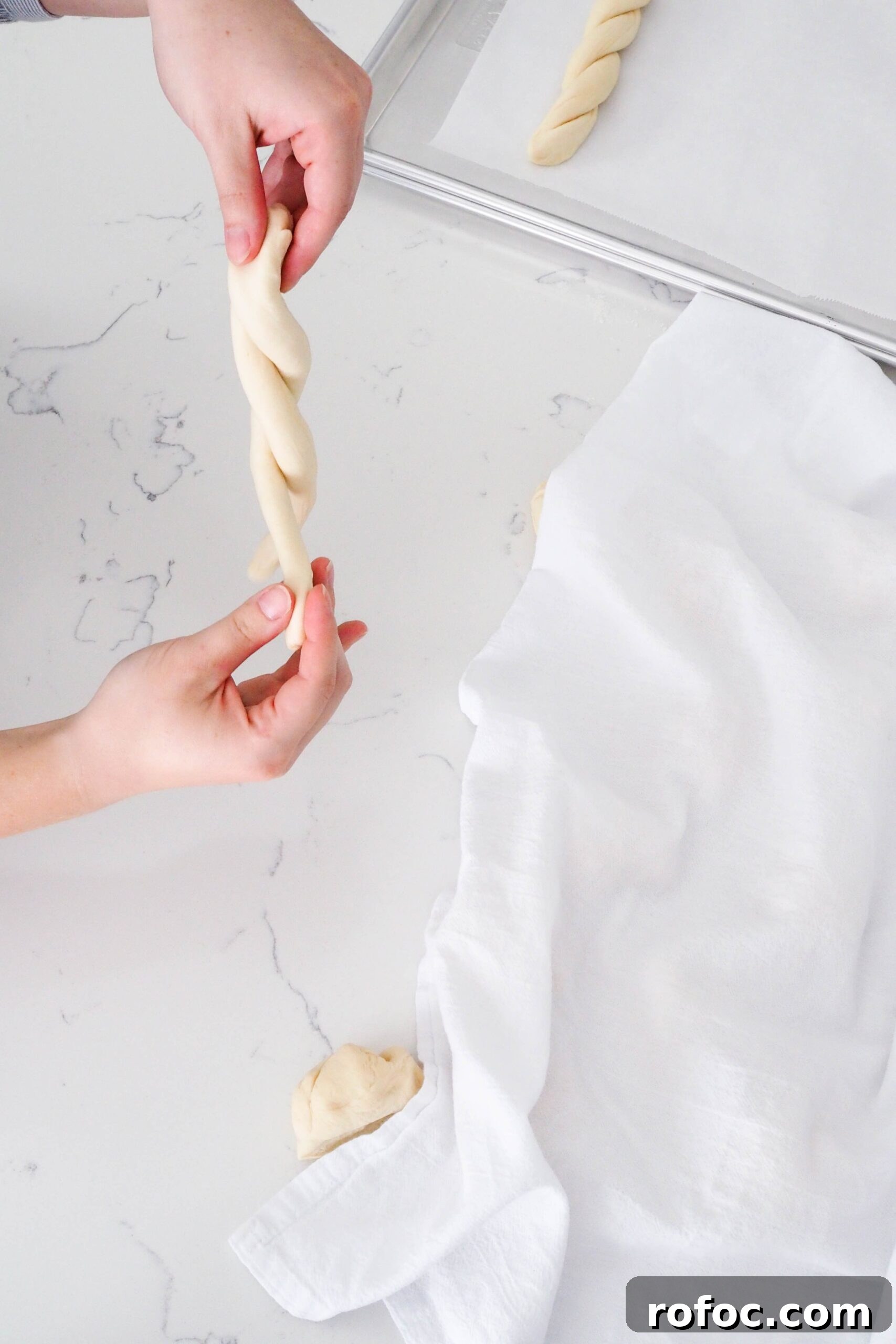 Crispy Garlic Breadsticks Recipe with Herb Butter Dip 11 Two hands twist a log of dough around another.