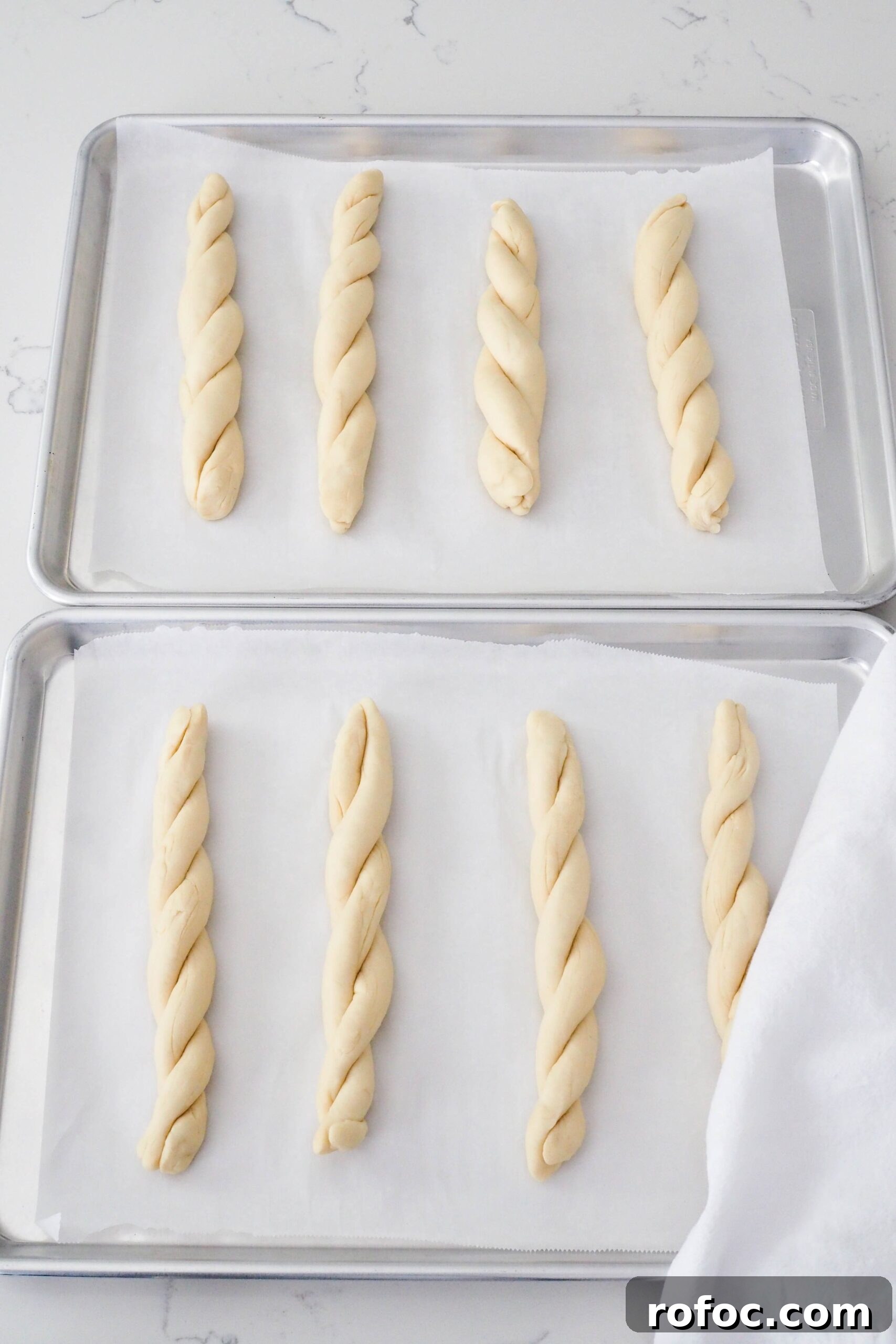 Crispy Garlic Breadsticks Recipe with Herb Butter Dip 12 Eight twisted garlic breadsticks on a baking sheet.