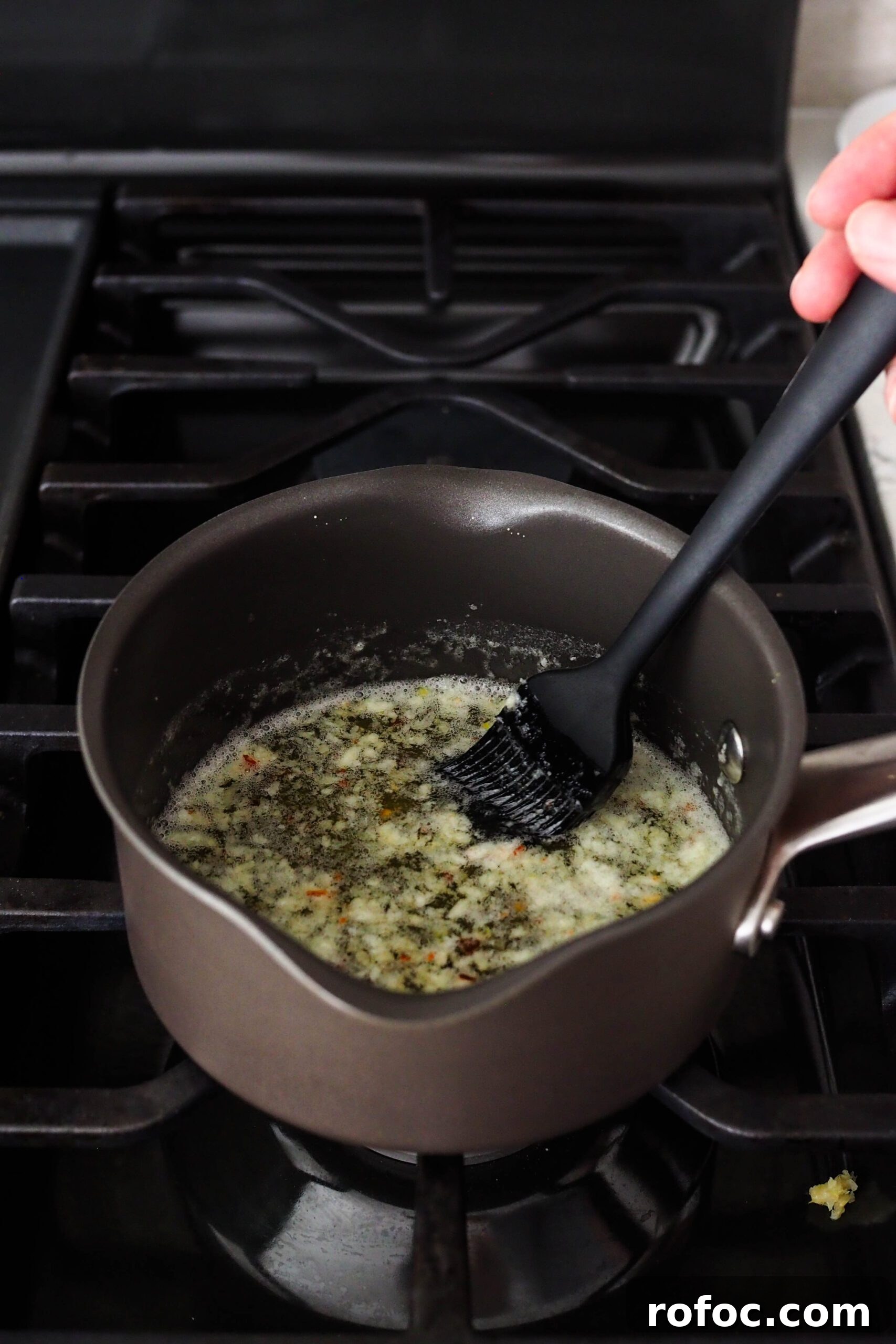Crispy Garlic Breadsticks Recipe with Herb Butter Dip 14 A pastry brush stirs garlic into butter in a small saucepan.
