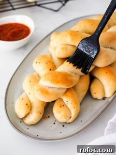 Crispy Garlic Breadsticks Recipe with Herb Butter Dip 18 A silicone pastry brush brushes garlic butter onto twisted breadsticks.