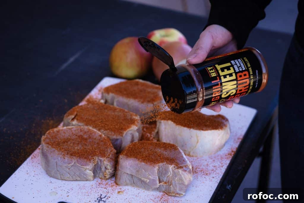 Grilled Pork Loin Chops with Caramelized Apples & Onions Recipe 4 A hand seasoning raw pork with Hey Grill Hey Sweet Rub.