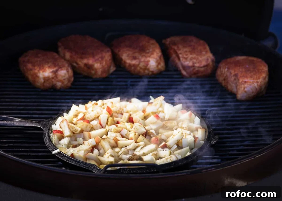 Grilled Pork Loin Chops with Caramelized Apples & Onions Recipe 6 Chipped apples in a cat-iron skillet on the grill next to BBQ pork.