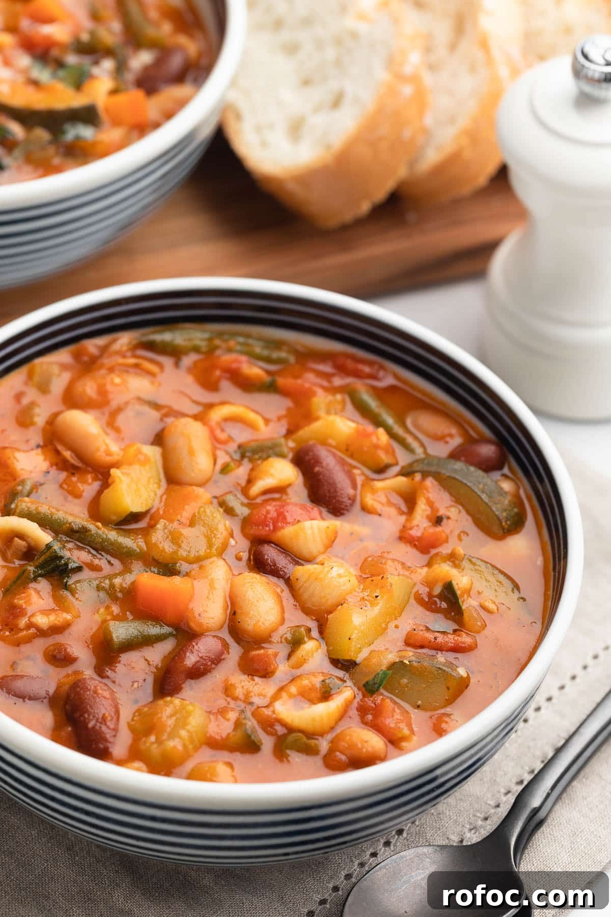 Classic Italian Minestrone Soup Recipe for Cozy Weeknight Dinners 2 minestrone soup in a blue and white striped bowl on a taupe napkin
