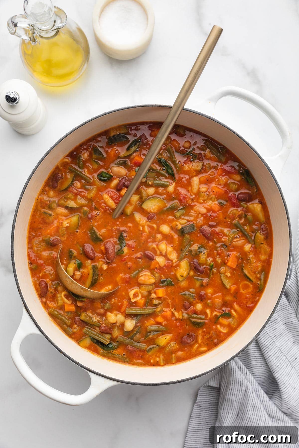 Classic Italian Minestrone Soup Recipe for Cozy Weeknight Dinners 15 overhead of a cooked minestrone soup in a white enameled cast iron Dutch oven with a gold ladle