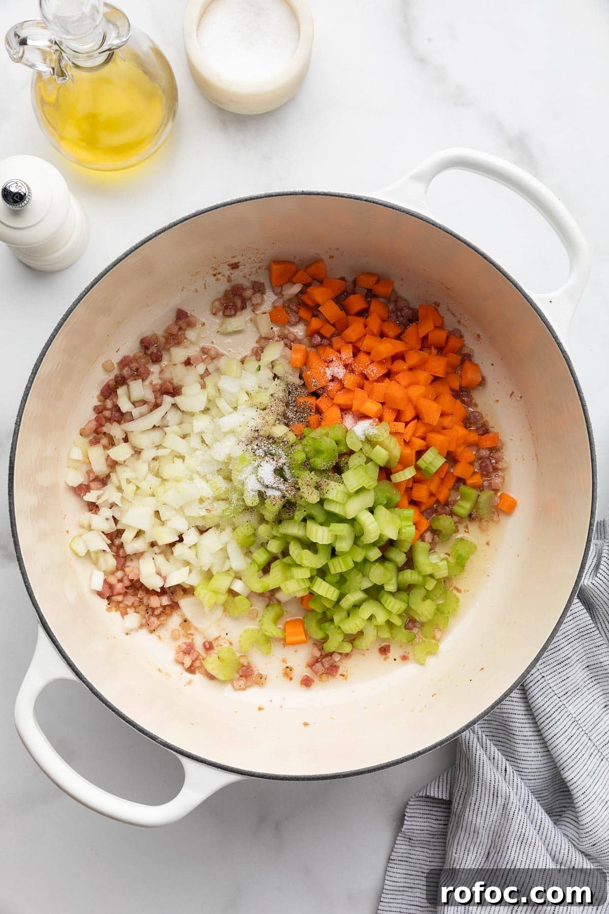 Classic Italian Minestrone Soup Recipe for Cozy Weeknight Dinners 7 diced celery, carrots, and onions in a white enameled cast iron Dutch oven with fried diced pancetta