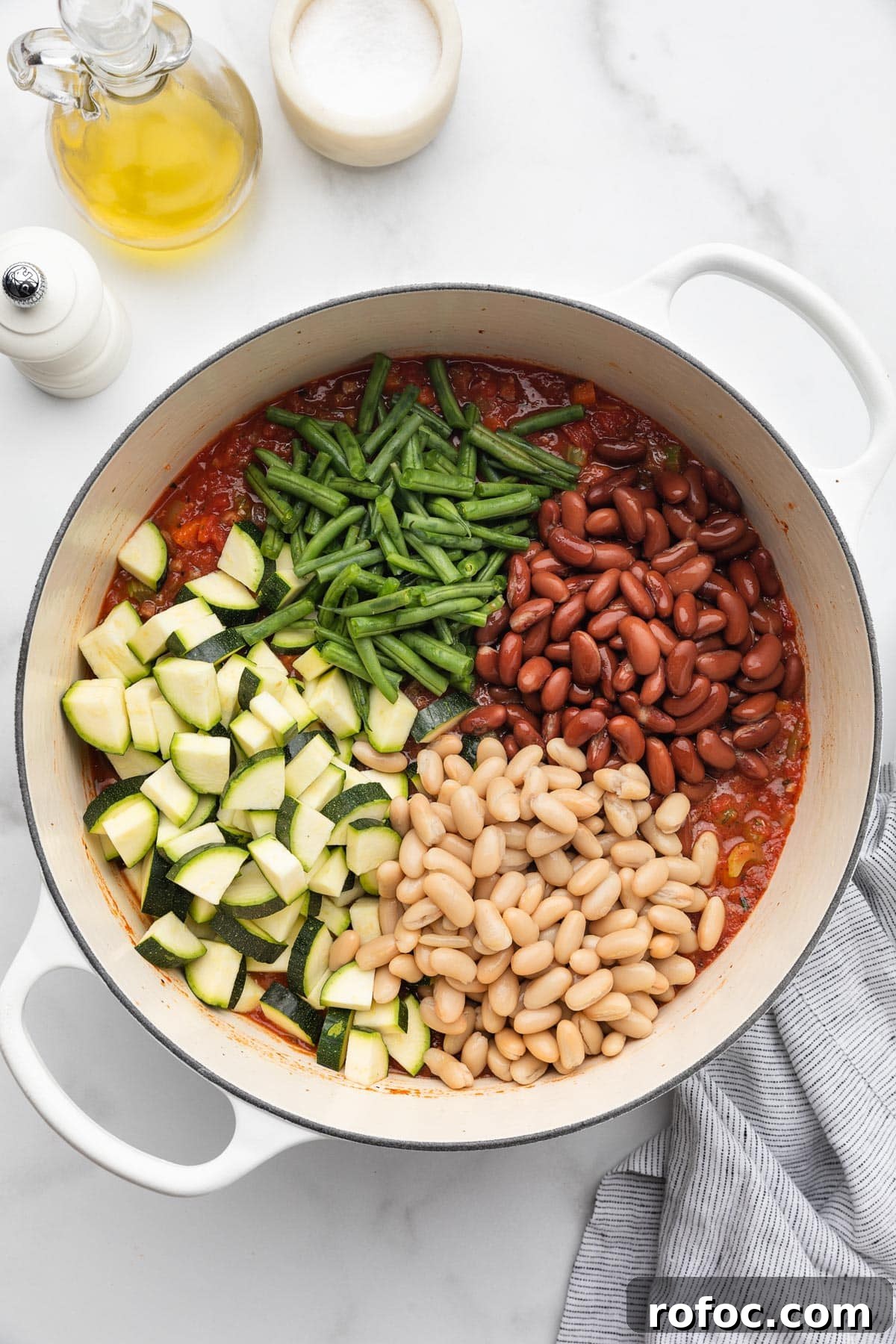 Classic Italian Minestrone Soup Recipe for Cozy Weeknight Dinners 10 piles of zucchini, green beans, kidney beans, and cannellini beans added to a pot of uncooked minestrone soup