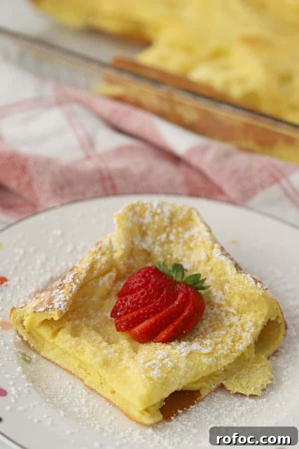 Fluffy German Pancake (Dutch Baby) Recipe + Video Guide 2 German Pancakes on a plate topped with powdered sugar and a fresh strawberry.