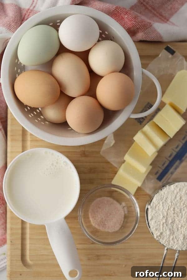 Fluffy German Pancake (Dutch Baby) Recipe + Video Guide 3 Ingredients for German Pancakes on a cutting board, including eggs, butter, milk, flour and salt.