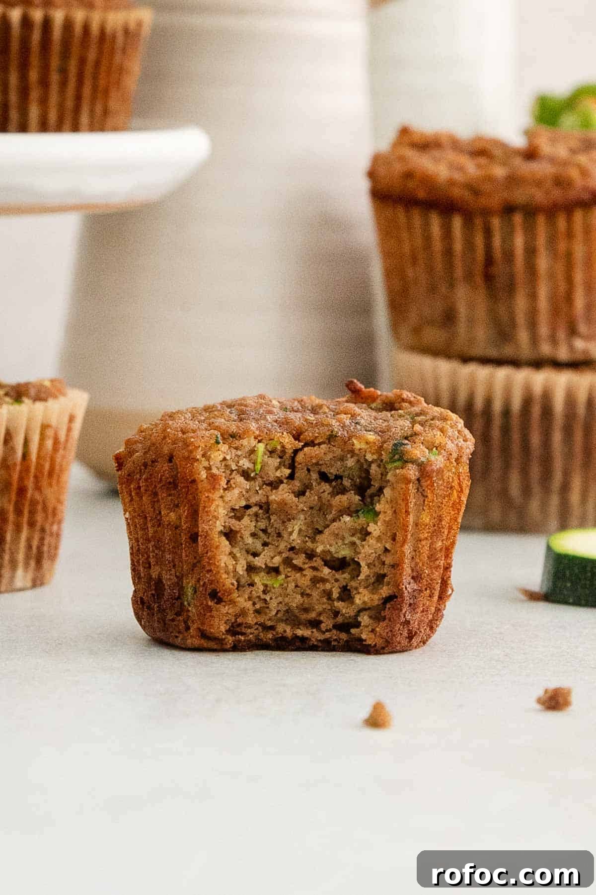 Gluten-Free Paleo Zucchini Muffins with Almond Flour 3 a paleo zucchini muffin with one bite missing and more muffins in background
