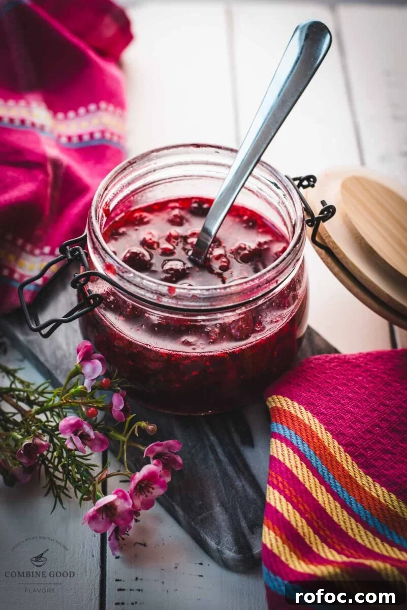 No-Cook Homemade Raspberry Syrup Recipe for Fresh, Intense Flavor 9 Preserving jar, filled with delicious uncooked raspberry syrup placed on a marbled plate.