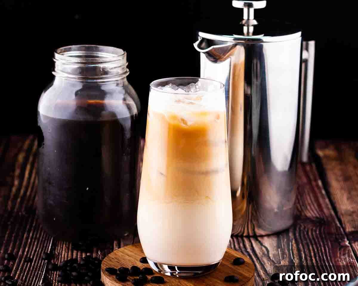 Homemade Vanilla Sweet Cream Cold Brew Recipe You’ll Love 12 A tall glass of vanilla sweet cream cold brew with a mason jar of cold brew concentrate in the background with a French press coffee pot.