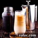Homemade Vanilla Sweet Cream Cold Brew Recipe You’ll Love 14 A tall glass of vanilla sweet cream cold brew with a mason jar of cold brew in the background and a french press.