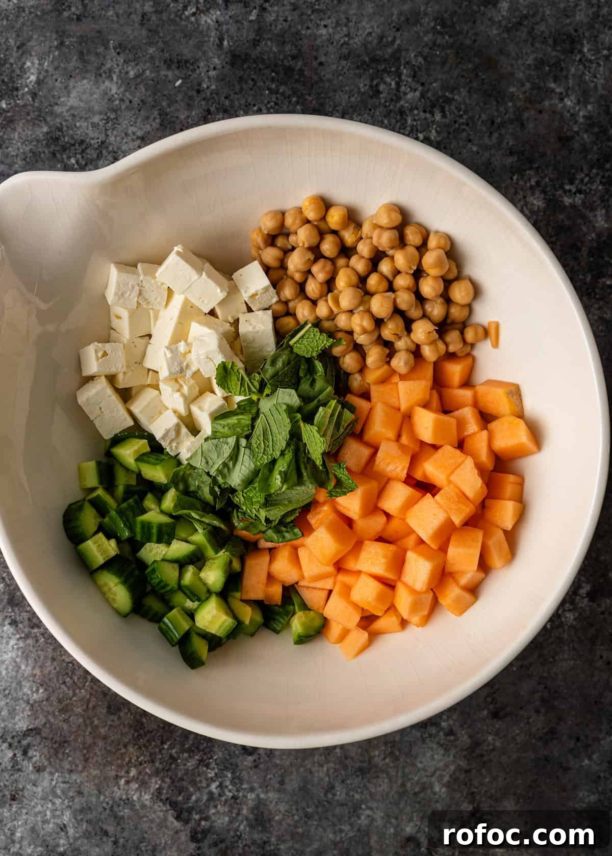 overhead: melon salad ingredients in a large bowl before mixing
