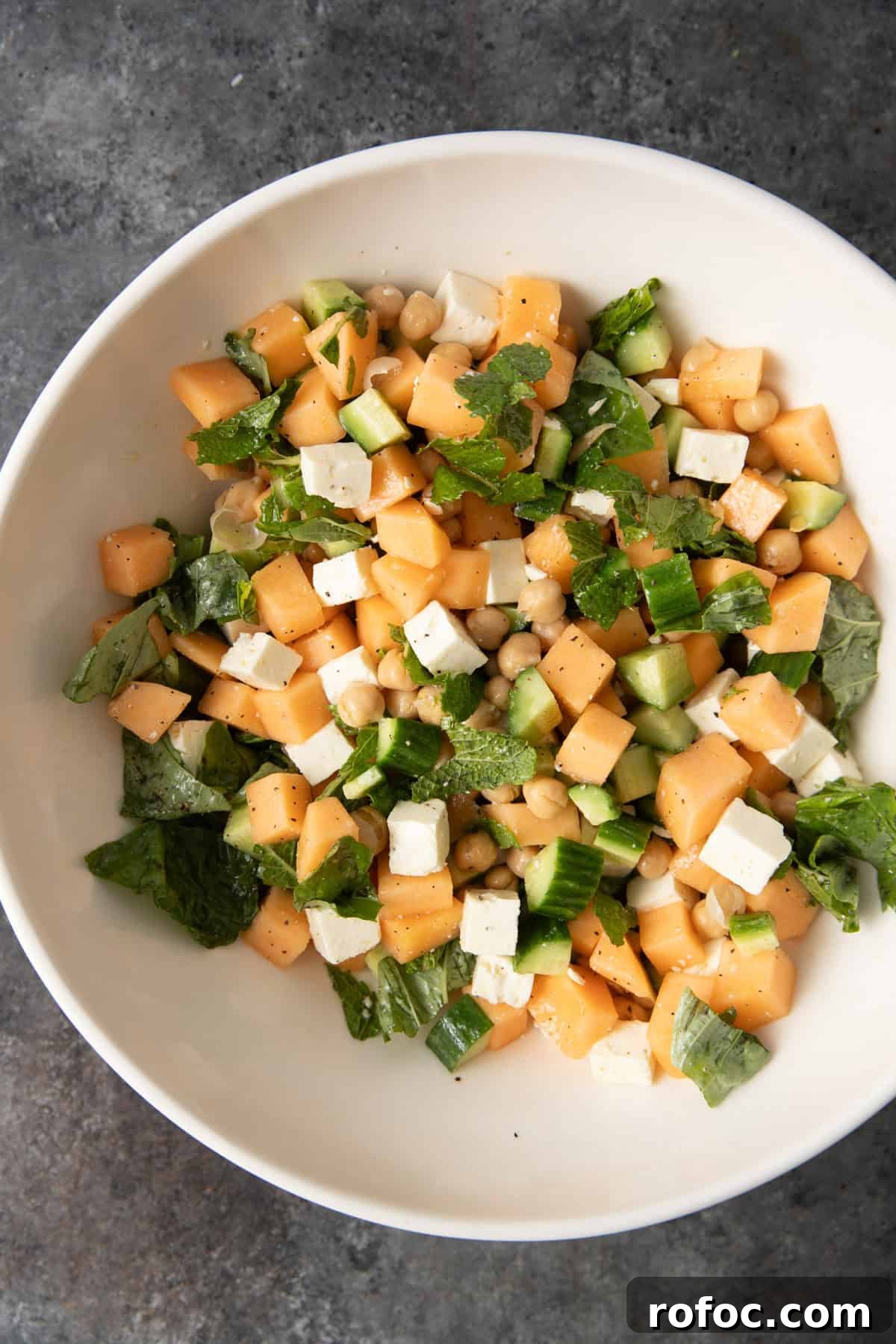 overhead: cantalope salad ingredients in a large bowl before mixing