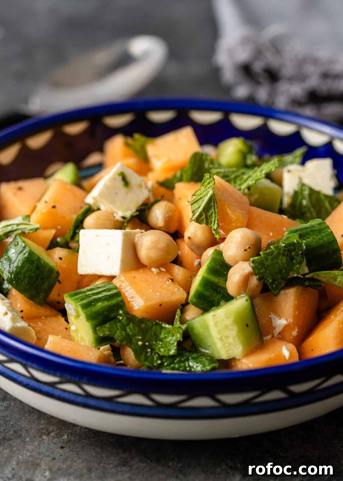 side view closeup: cantalope salad in a bowl with cucumbers, chickpeas, and feta