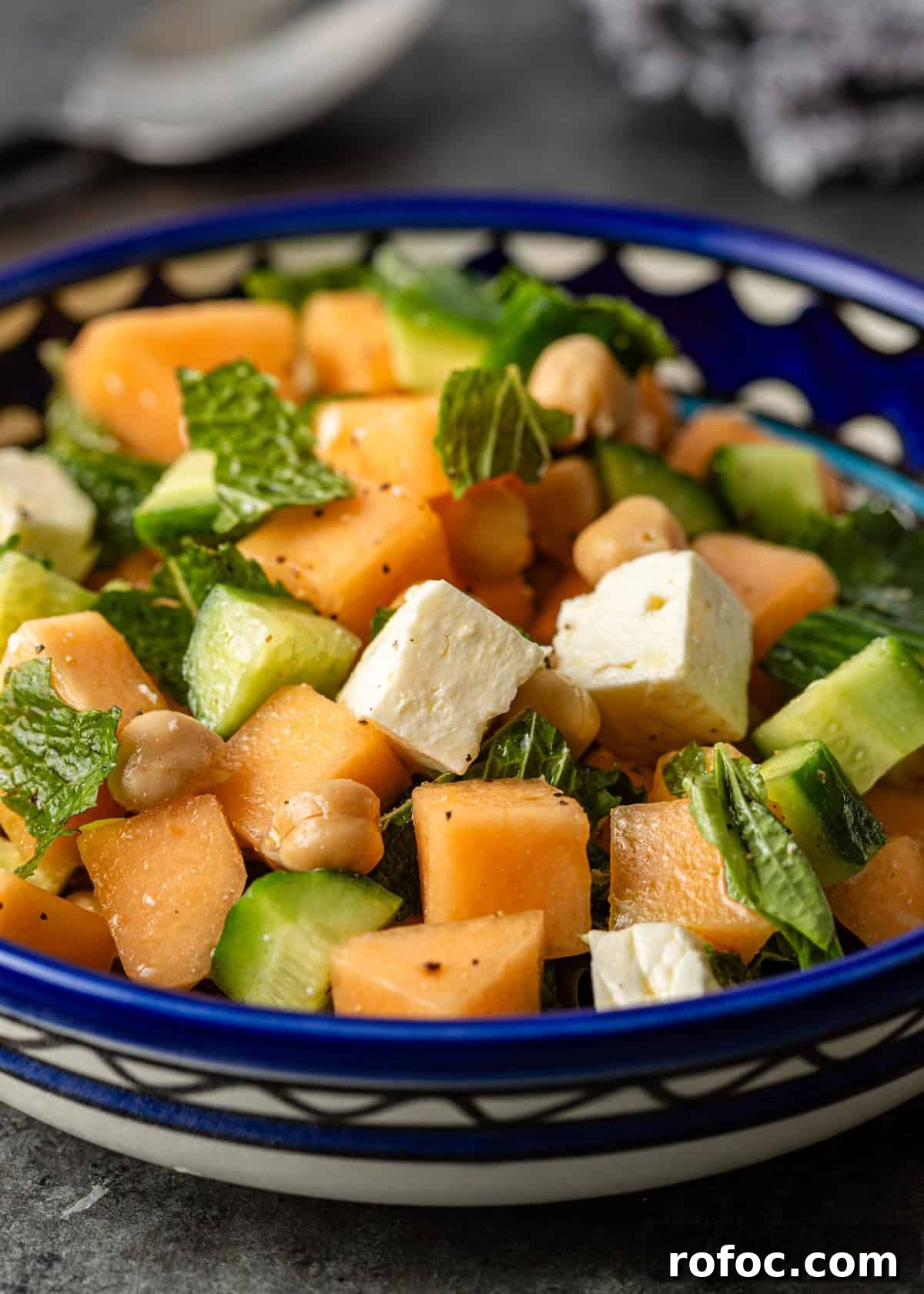 closeup: melon salad with fresh herbs, chickpeas, cucumbers, and feta