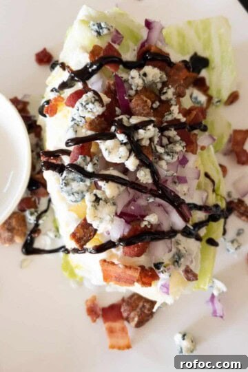 steakhouse wedge salad covered with blue cheese and balsamic glaze on white plate