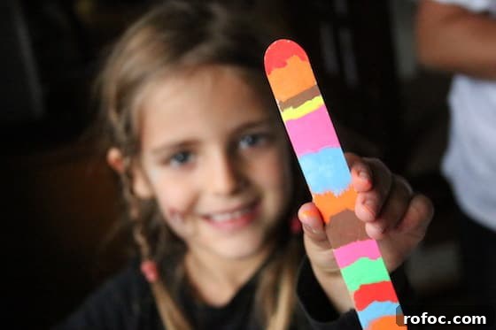 Colorful Chalk Marker Bookmarks Kids Can Create 3 Child holding craft stick bookmark