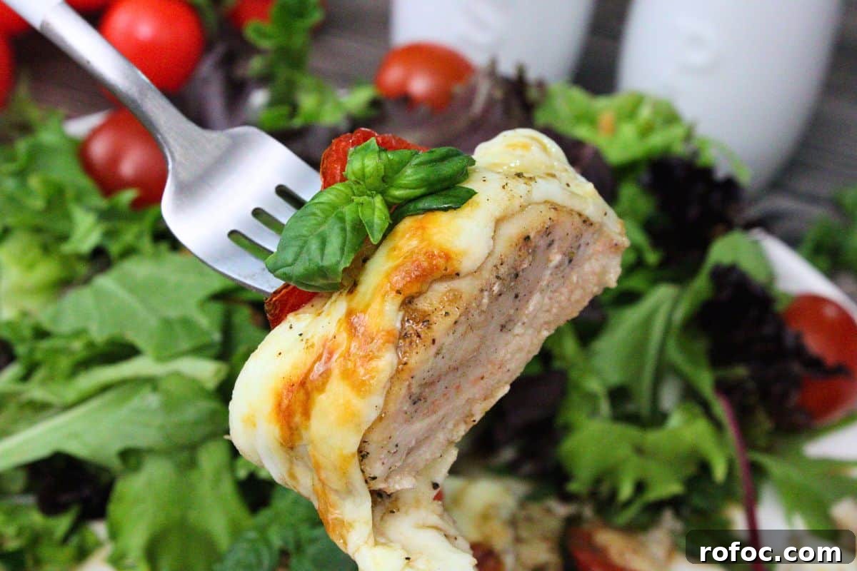 11 Creative Air Fryer Tomato Recipes for Flavorful Meals 10 holding up a fork with a piece of juicy air fryer hasselback chicken topped with mozzarella and tomato