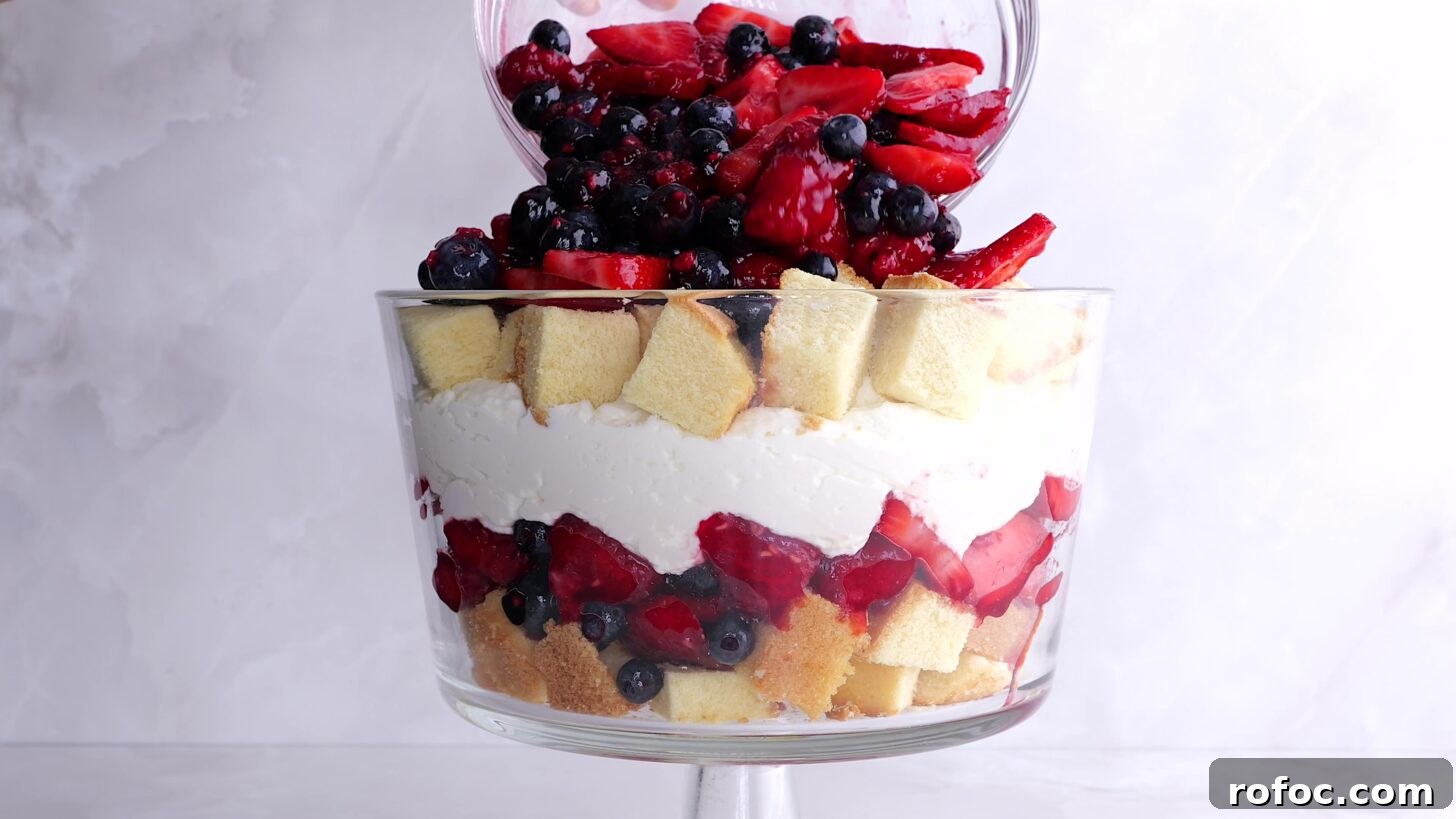 No-Bake Summer Berry Trifle Recipe: Pretty, Crowd-Pleasing Dessert 3 Jam coated berries being poured into berry trifle dish