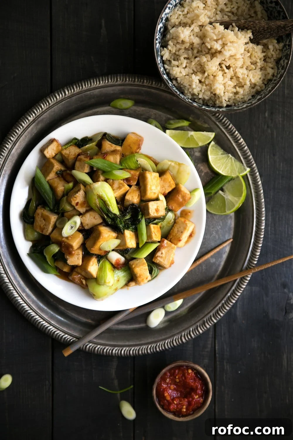 Crispy Tofu with Garlic Bok Choy Stir-Fry 3 Spicy Stir Fried Tofu with Bok Choy plated with a bowl of rice on the side with a small dish of chili paste