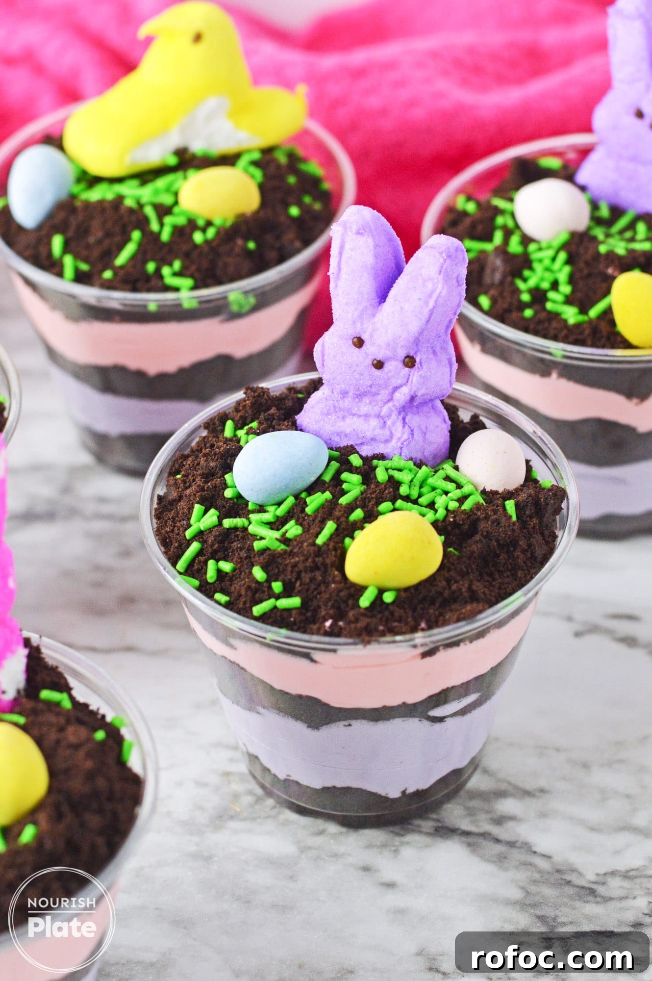 Easter Dirt Cup Treats: Chocolate Pudding Parfaits with Oreo Soil 6 Easter dirt cups with layered instant pudding in colors, topped with peeps and mini eggs.