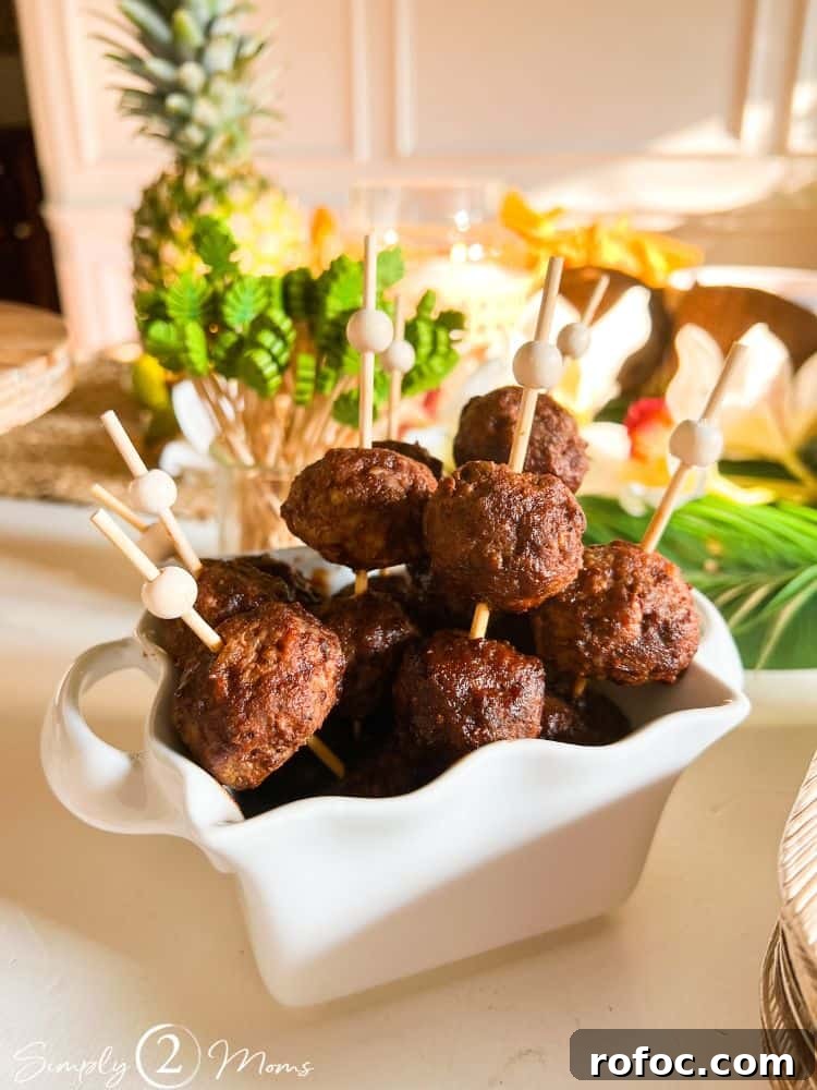 9 Tropical Cocktail Appetizers for Your Next Party 5 Tropical cocktail meatballs on bamboo skewers with a wood bead on the end displayed in a serving dish.