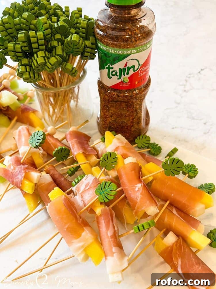 9 Tropical Cocktail Appetizers for Your Next Party 7 Jicama and mango wrapped in prosciutto on cocktail picks with monstera leaf tops and a bottle of Tajin.