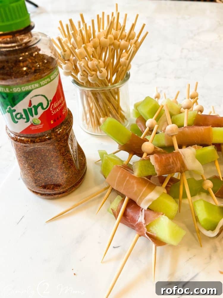9 Tropical Cocktail Appetizers for Your Next Party 10 Bottle of Tajin next to slices of honeydew melon wrapped with prosciutto held by cocktail picks with bamboo beads.