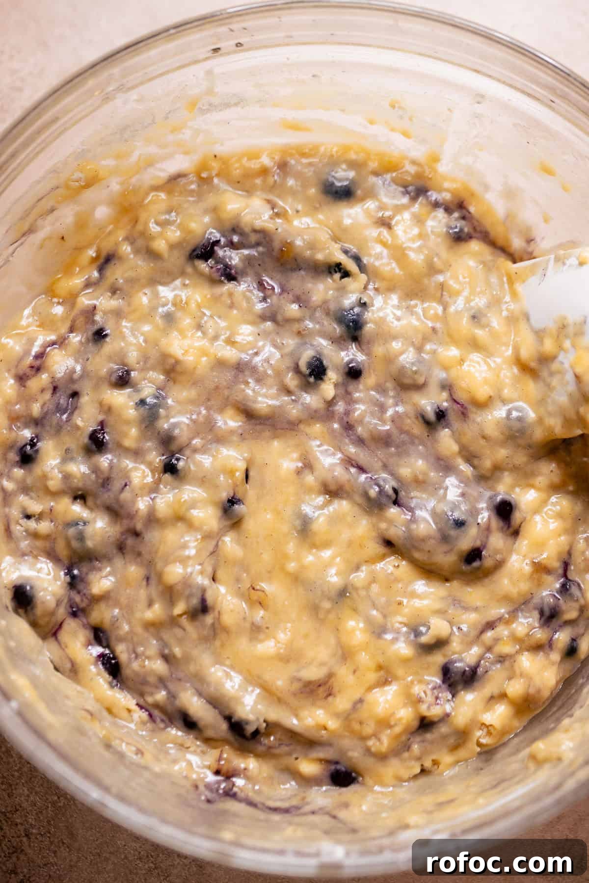 Thick banana bread batter with blueberries folded into the mixture.