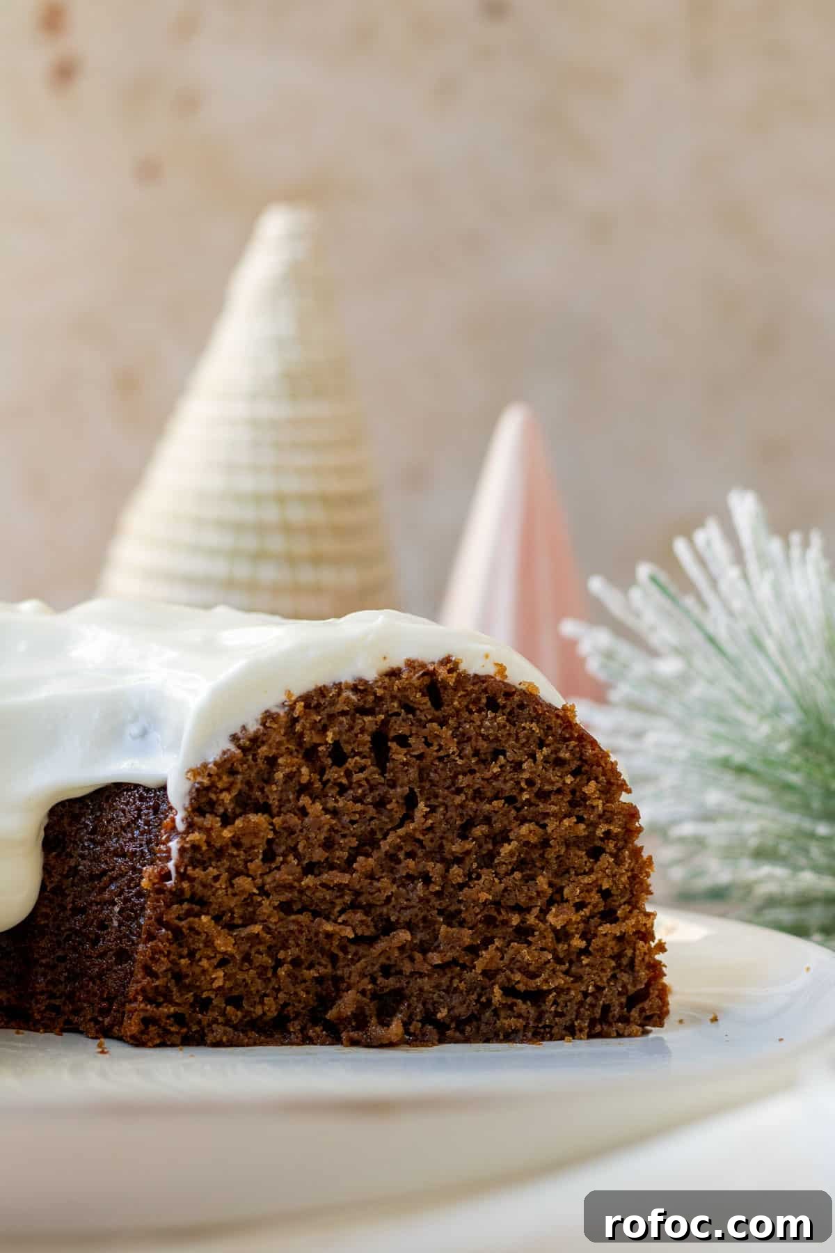 Gingerbread Bundt Cake with Silky Cream Cheese Glaze 3 close up of a gingerbread bundt cake sliced open with decorative christmas trees in the background
