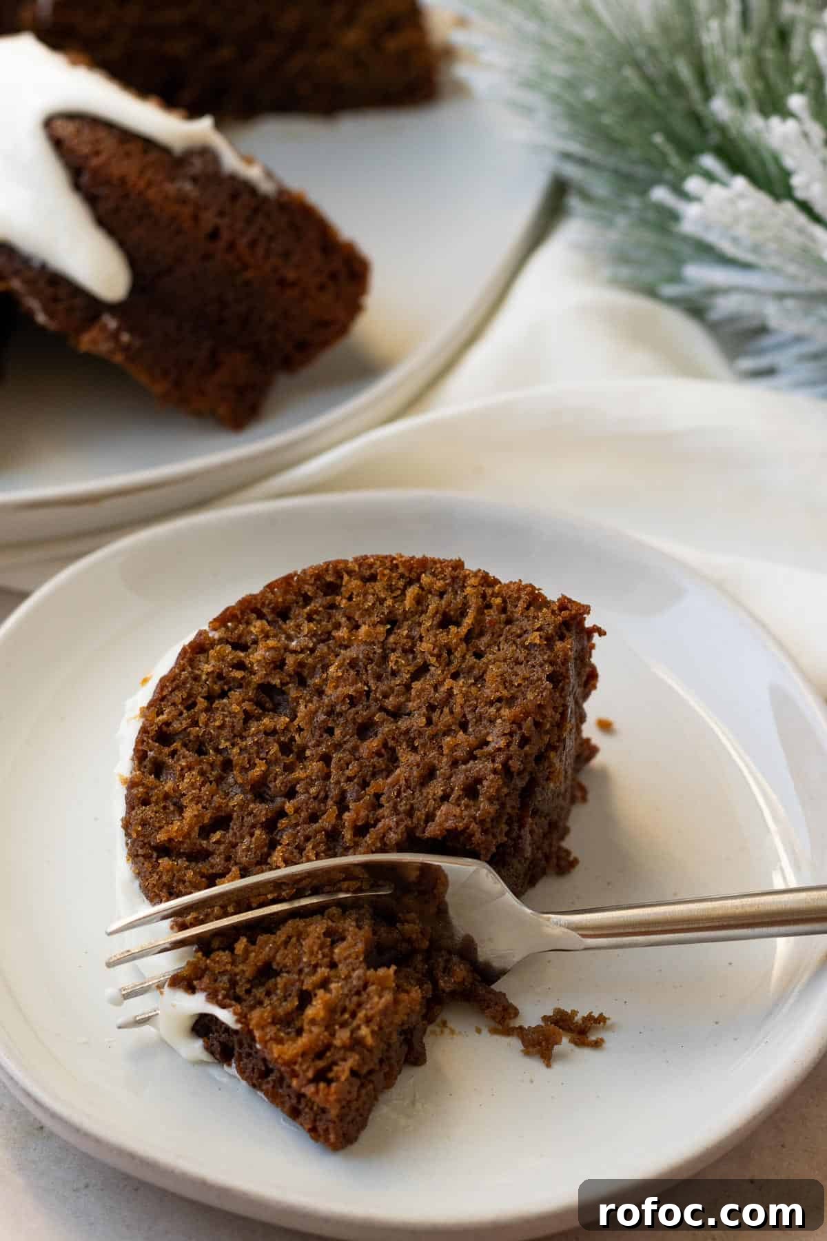 Gingerbread Bundt Cake with Silky Cream Cheese Glaze 5 slice of gingerbread cake on a white plate with a fork