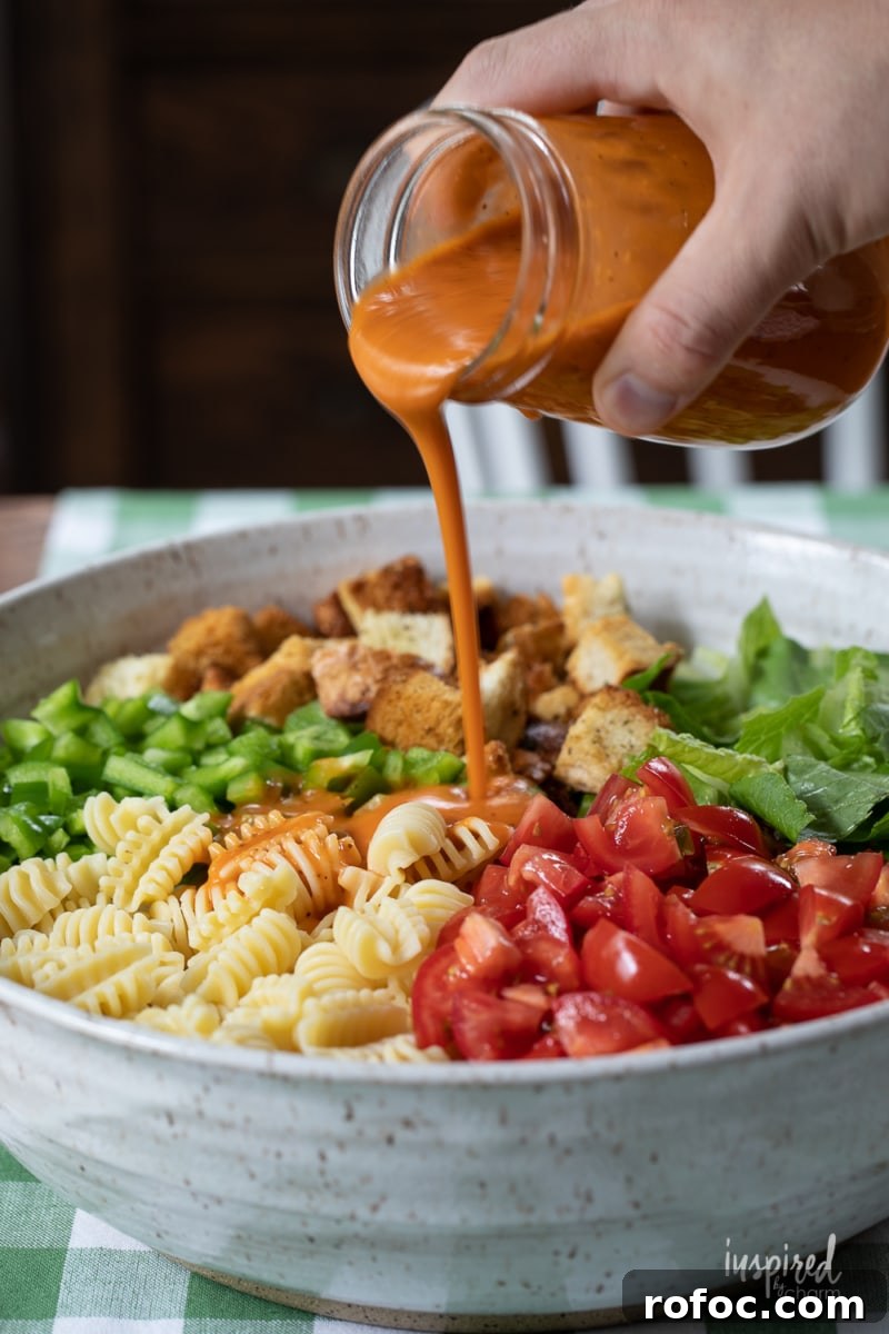 Radiatori Pasta Salad with Fresh Herbs and Lemon Vinaigrette 8 pouring den dressing onto salad.