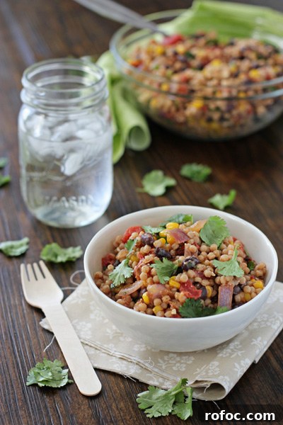 Two bowls filled with Mexican Couscous Salad and a glass of water.