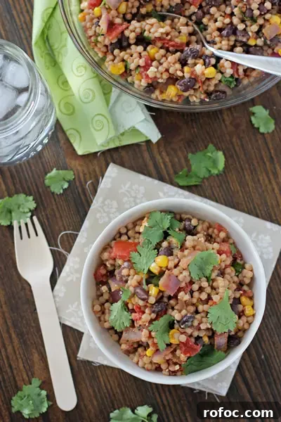A white bowl filled with Mexican Couscous with a fork to the side.