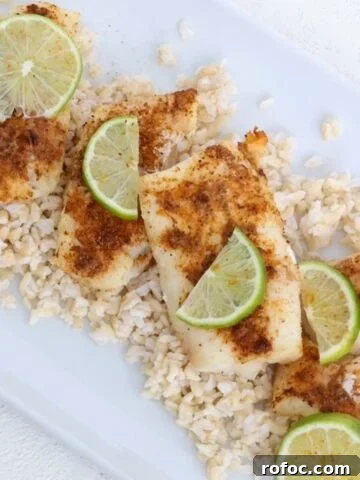 Air-fried cod topped with seasoning and slices of fresh lime on a white dish.