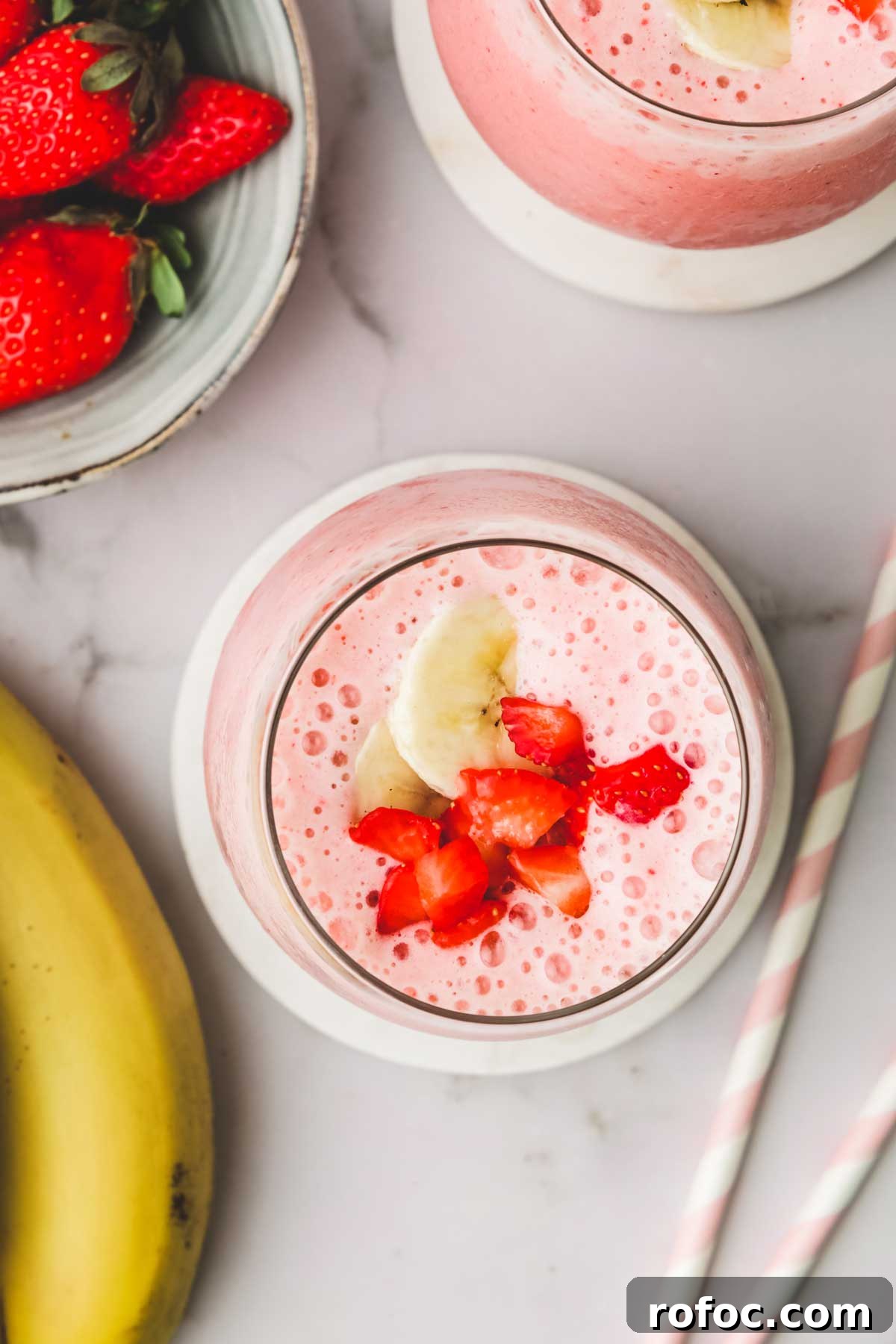 Strawberry Banana Smoothie Recipe — Creamy Fresh Blend 4 Un verre de smoothie avec des morceaux de banane et des fraises