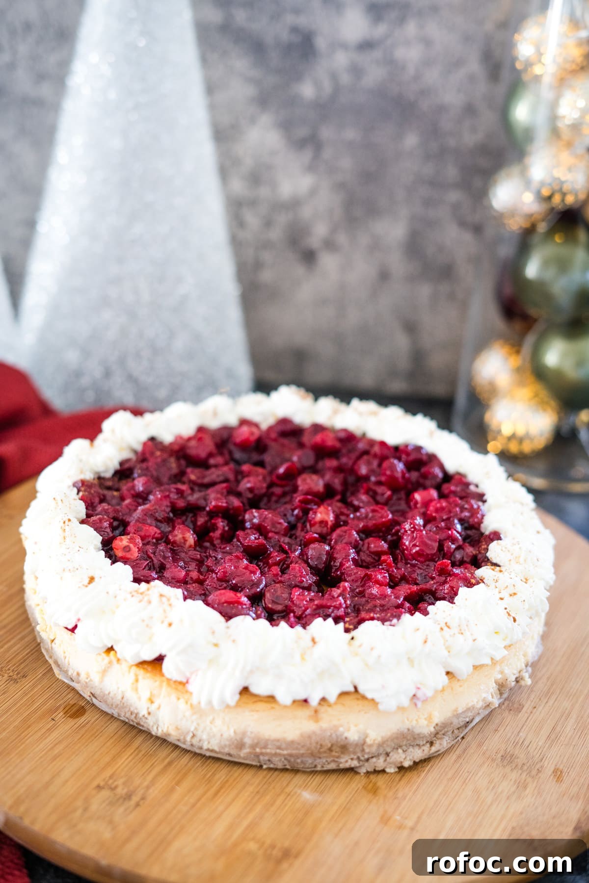 Low-Carb Cranberry Cheesecake: Keto Holiday Dessert Recipe 11 A scrumptious cranberry cheesecake delicately plated on a rustic wooden cutting board.