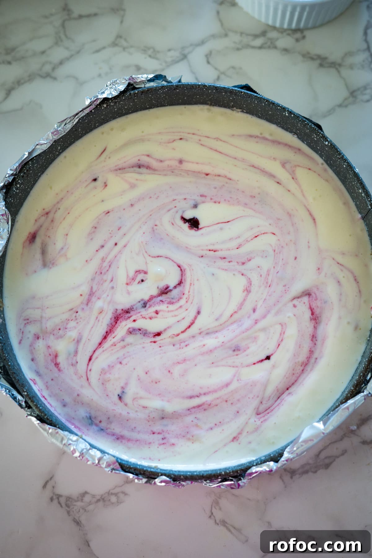 Low-Carb Cranberry Cheesecake: Keto Holiday Dessert Recipe 9 A cranberry cheesecake in a pan on a marble counter.