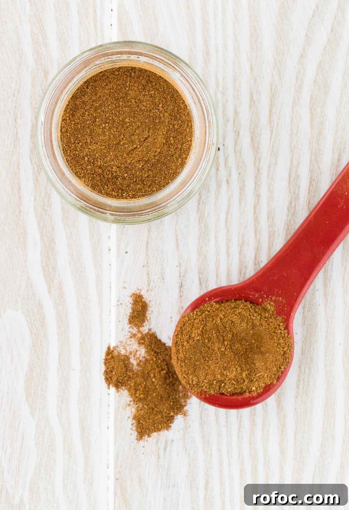 Homemade Apple Pie Spice Mix You Can Make in Minutes 2 Apple pie spice mixture on a spoon, and in a jar on a white wooden background.