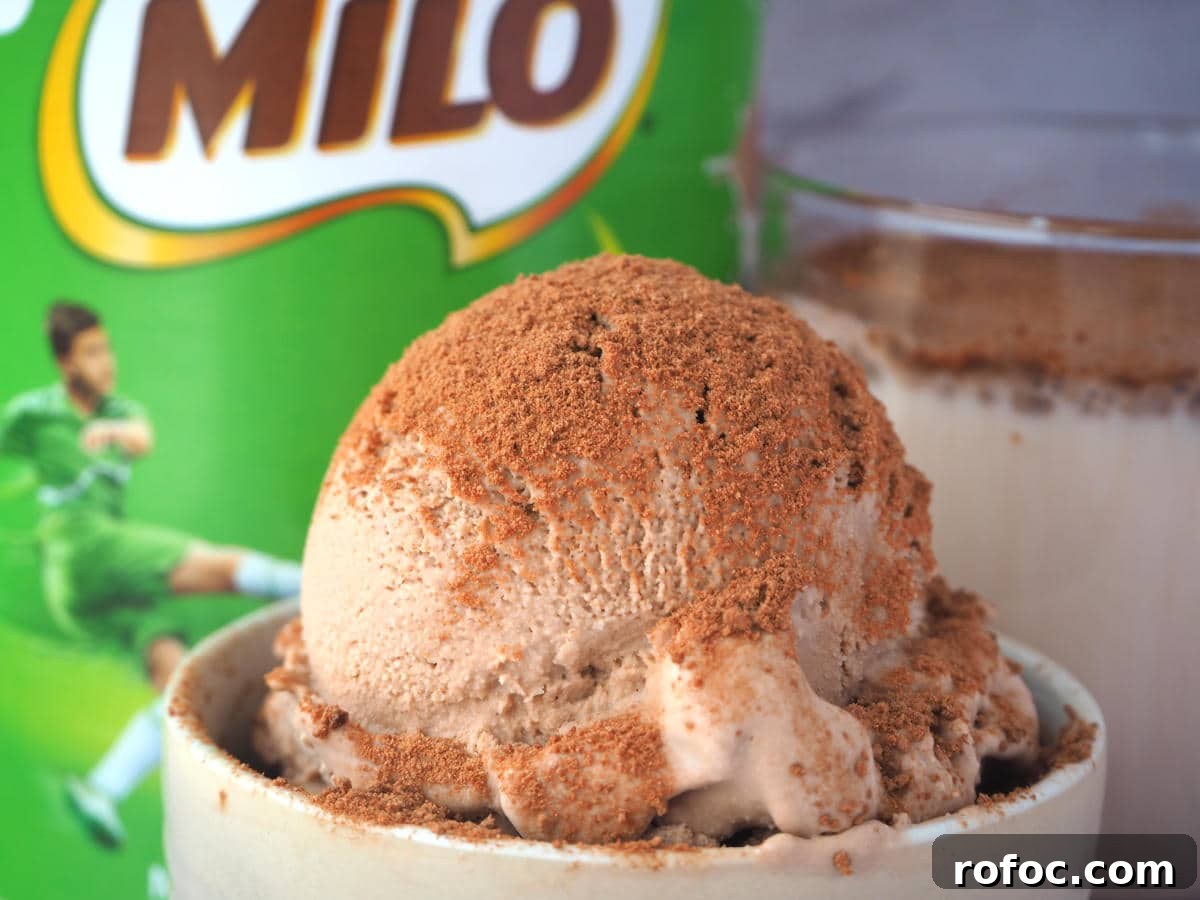 Creamy Milo Ice Cream Recipe: Homemade Milo Frozen Treat 2 Close up scoop Milo ice cream sprinkled with Milo, in a small bowl, with Milo tin and glass of Milo in the background.