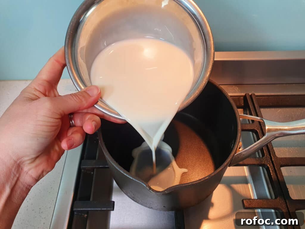 Creamy Milo Ice Cream Recipe: Homemade Milo Frozen Treat 4 adding milk to ice cream mix in pot on stove.