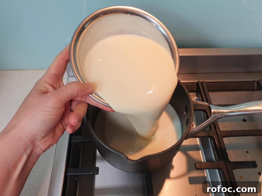Creamy Milo Ice Cream Recipe: Homemade Milo Frozen Treat 5 adding cream to ice cream mix in pot on stove.