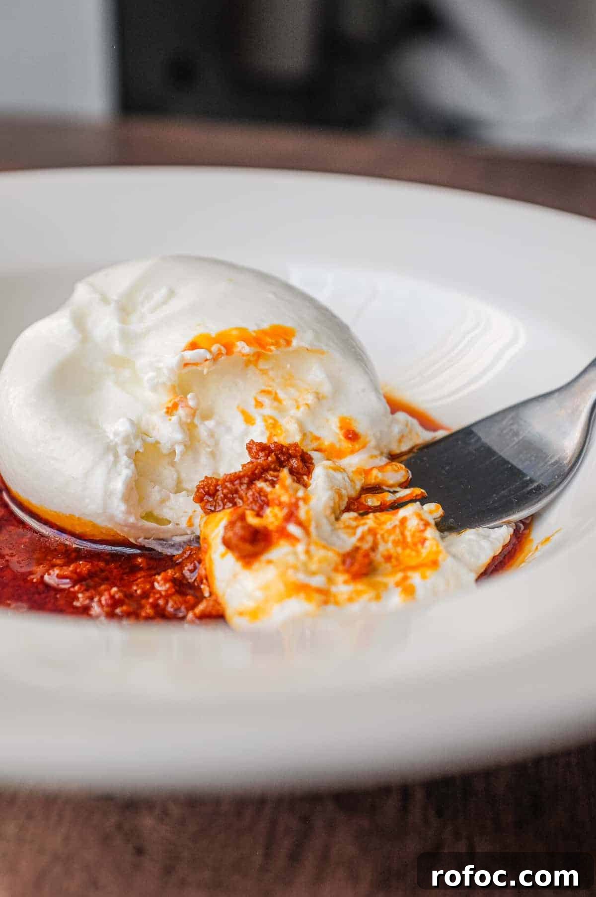 Nduja with Burrata | cookeatworld.com A plate of nduja sausage in liquid form, topped with a ball of burrata cheese and garnished with a small sprig of basil. A fork sits in the sauce.