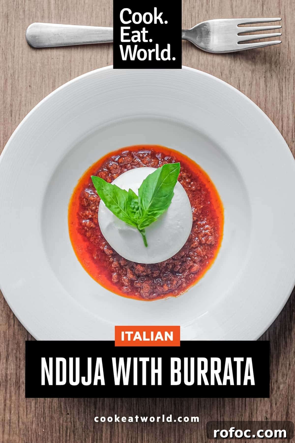 Nduja with Burrata | cookeatworld.com A plate of nduja sausage in liquid form, topped with a ball of burrata cheese and garnished with a small sprig of basil.
