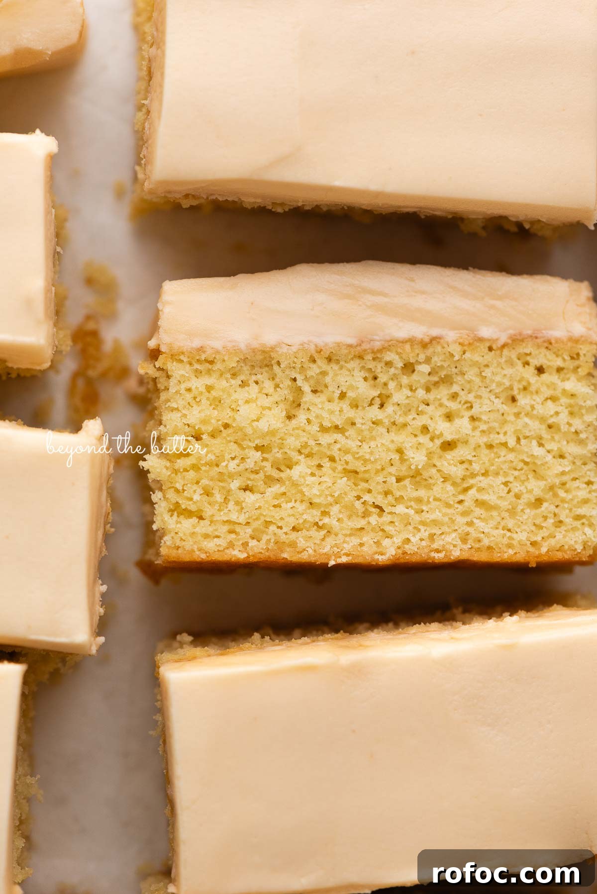 Rectangular slices of butterscotch krimpets placed on a parchment paper lined background with center slice on its slide.