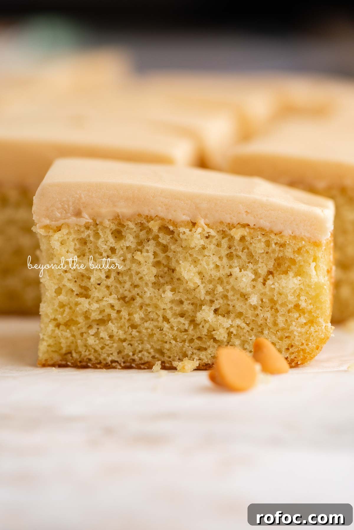 Rectangular slices of butterscotch krimpets placed on a parchment paper lined background with two butterscotch chips in foreground.