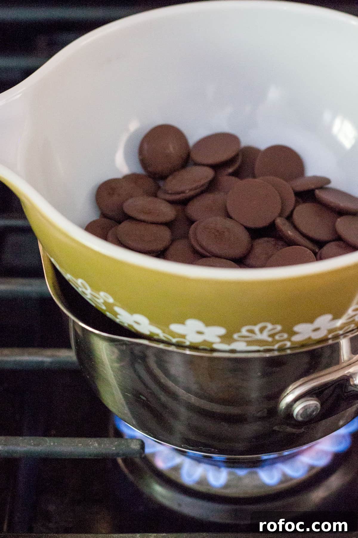 Melting dark chocolate wafers in a bowl set over a pot of water.